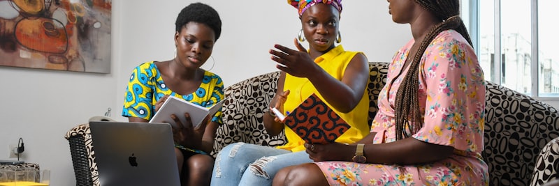a group of people sitting on a couch looking at a laptop