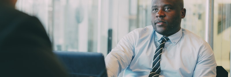 African American businessman in formal wear explaining his startup plan to partner in glassy cafe during lunch time